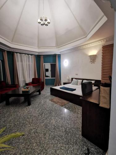 a bedroom with a bed and a couch and a table at L'Address in Cotonou