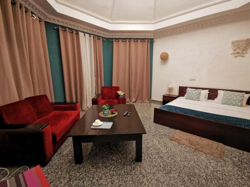 a room with a bed and a couch and a table at L'Address in Cotonou