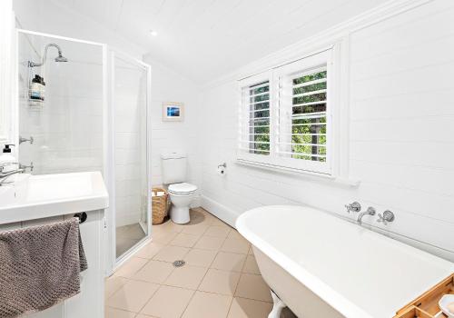 baño blanco con bañera y aseo en Boat Harbour Store Cottage, en Gerringong