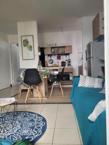 a living room with a blue bed and a kitchen at Escale 86 in Sainte-Marie