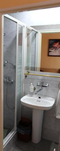 a bathroom with a sink and a shower with a mirror at Hotel Sportowy in Ostrzeszów