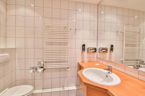 a bathroom with a sink and a toilet and a mirror at Hotel & Restaurant Zur Zwiebel in Peenemünde