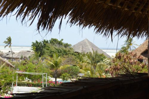 a view of the beach and some straw umbrellas at Pole Pole Beach House in Watamu