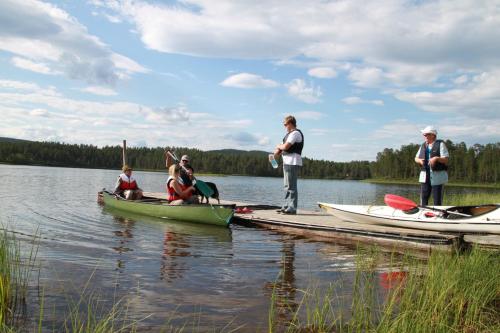 a group of people on a dock with boats on a lake at Lemmenjoen Lumo - Nature Experience & Accommodation in Lemmenjoki