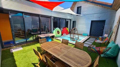 une terrasse avec une table et des chaises ainsi qu'une aire de jeux dans l'établissement Le Loft, à Riorges