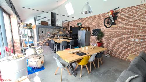 Cette chambre est dotée de tables, de chaises et d'un mur en briques. dans l'établissement Le Loft, à Riorges