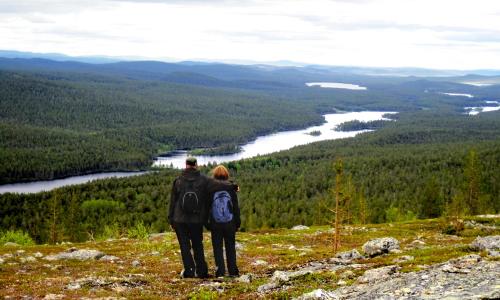 a man and a woman standing on top of a mountain at Lemmenjoen Lumo - Nature Experience & Accommodation in Lemmenjoki