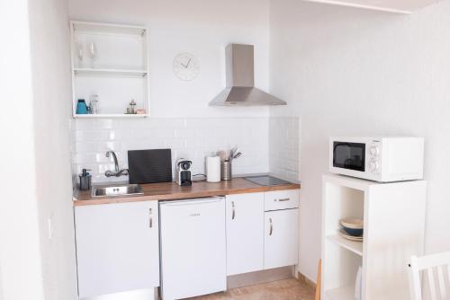 een keuken met witte kasten en een magnetron bij Wohnung Buganvilla in Agüimes
