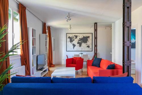 a living room with a blue couch and red chairs at Confortable piso 3 habitaciones en Retiro Atocha in Madrid