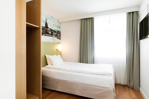 a hotel room with a bed and a window at Good Morning+ Göteborg City in Gothenburg