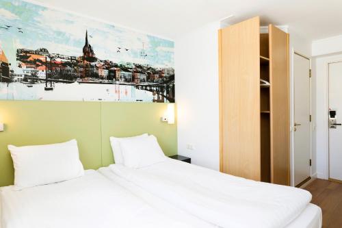 a bedroom with a white bed and a painting on the wall at Good Morning+ Göteborg City in Gothenburg