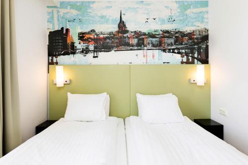 two beds in a room with a painting on the wall at Good Morning+ Göteborg City in Gothenburg