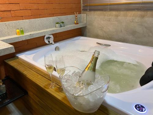 Una bañera con una botella de champán y copas de vino. en Cabana I com Banheira Hidro e Lareira - Chalet Mont Blanc - Urubici, en Urubici