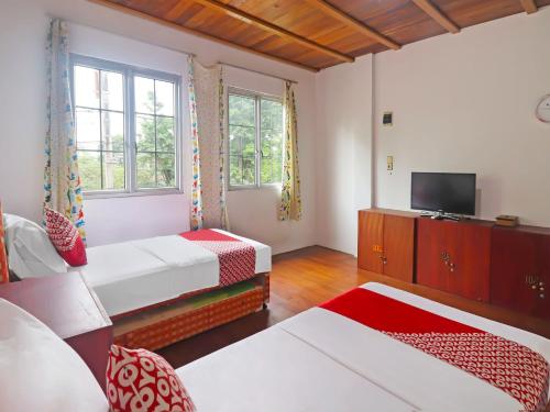 a hotel room with two beds and a television at OYO 91807 Kemalasari Guesthouse in Jambi