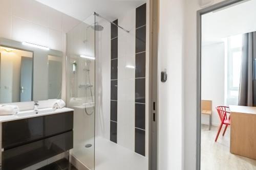 a bathroom with a glass shower and a sink at Residhotel Le Central'Gare in Grenoble