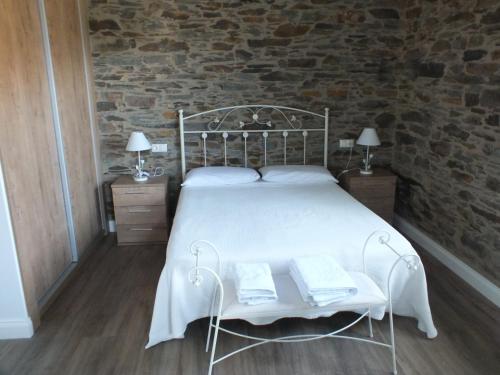 a bedroom with a white bed with two tables and two lamps at Apartamentos Puerta del Castro in Coaña