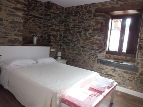a bedroom with a white bed and a brick wall at Apartamentos Puerta del Castro in Coaña