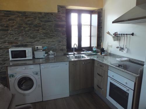 a kitchen with a sink and a washing machine at Apartamentos Puerta del Castro in Coaña