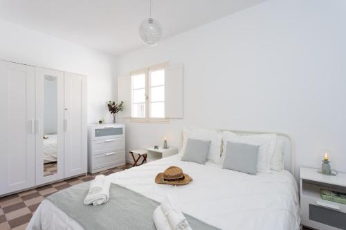 un dormitorio blanco con una cama con sombrero en Home2Book La Casita del Mercado, en Santa Cruz de Tenerife