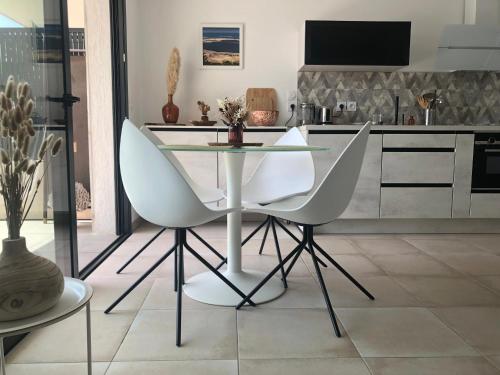 a kitchen with a glass table and two white chairs at Superbe Appartement T2 avec Piscine et Vue Mer in Fréjus
