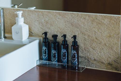 a group of black bottles sitting on a counter next to a sink at SEKIYA RESORT Terrace Midoubaru in Beppu