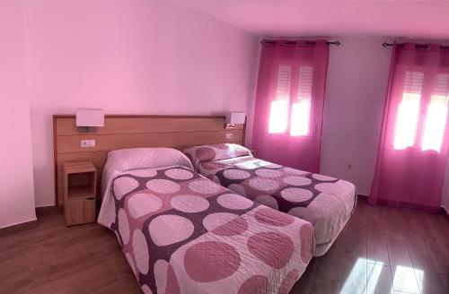 two beds in a bedroom with pink curtains at ALOJAMIENTOS AGAVE in Tabernas
