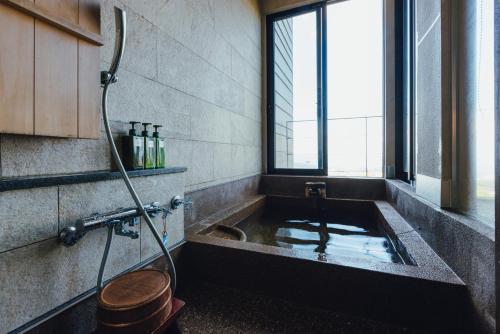 a bathroom with a bath tub with a shower at SEKIYA RESORT Terrace Midoubaru in Beppu