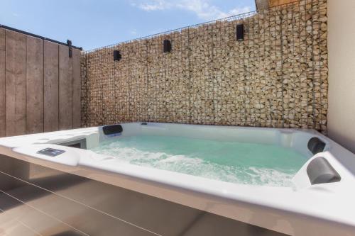 a bath tub in a bathroom with a stone wall at Cap d'Eau in Waasmunster