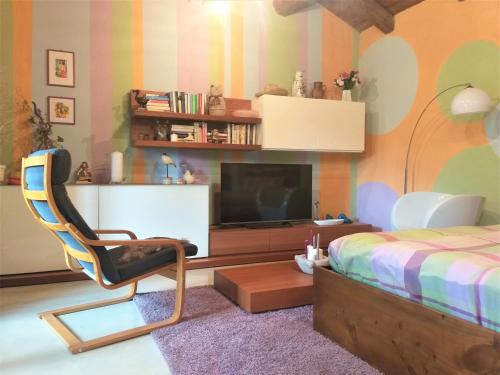 een slaapkamer met een bed, een stoel en een televisie bij LA CASA DI GILINDO in Roccabruna