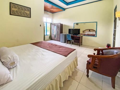 Schlafzimmer mit einem Bett, einem Schreibtisch und einem Stuhl in der Unterkunft Capital O 91806 Hotel Batu Suli in Palangkaraya