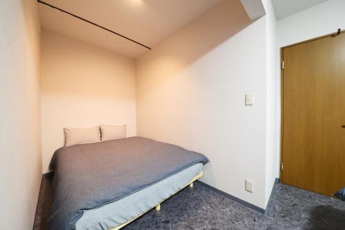 een slaapkamer met een bed in de hoek van een kamer bij NY Cottage A in Tokyo