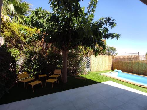 une cour avec un arbre et des chaises ainsi qu'une piscine dans l'établissement Villa Spa Béziers 4 étoiles ressourcez-vous avec style, à Béziers