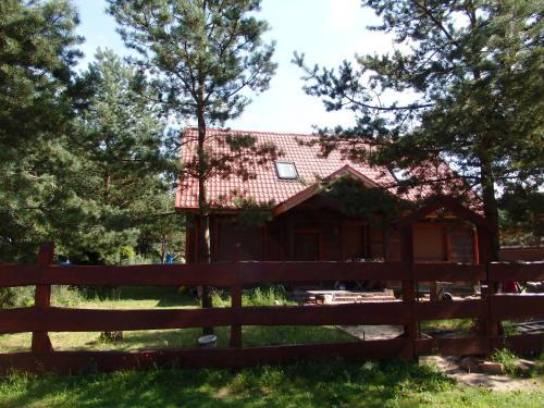 a log cabin behind a fence at Trójmiasto nad jeziorem DOM -ECHOCHATA in Kamień