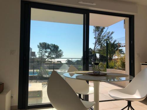 a dining room with a table and chairs in front of a window at Superbe Appartement T2 avec Piscine et Vue Mer in Fréjus