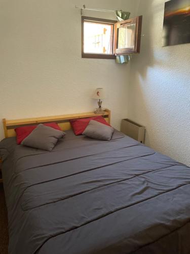 um quarto com uma cama grande e 2 almofadas em Appartement pour 6 personnes au pied des pistes au calme aux Menuires les Asters em Les Menuires