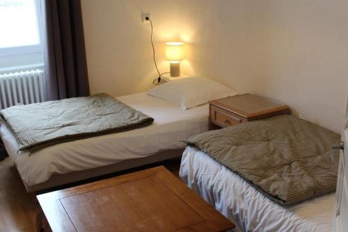 two beds in a small room with a lamp and a table at Hotel Le XIV in Pontorson