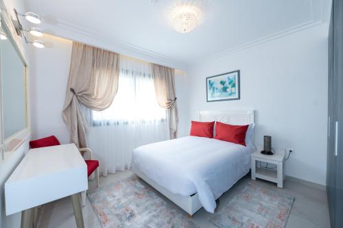 a white bedroom with red pillows and a bed at Villa Palmeraie Golf Agadir in Agadir