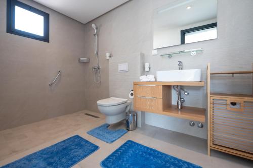 a bathroom with a sink and a toilet with blue rugs at Villa Palmeraie Golf Agadir in Agadir