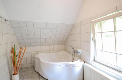 eine weiße Badewanne im Bad mit Fenster in der Unterkunft Ferien Hotel Villa Südharz in Sülzhayn