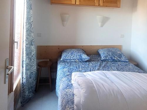 a bedroom with a bed with a blue comforter at Appartement plein cœur de vallandry in Landry