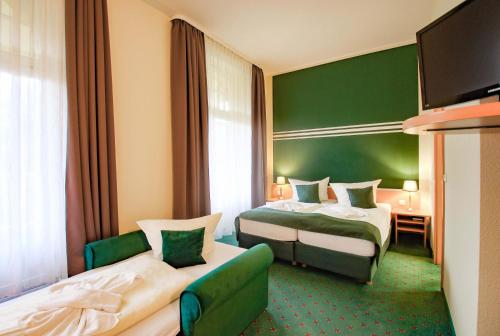 una habitación de hotel con 2 camas y una pared verde en Ferien Hotel Villa Südharz, en Sülzhayn