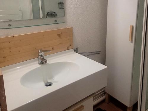 La salle de bains est pourvue d'un lavabo blanc et d'un miroir. dans l'établissement Appartement plein cœur de vallandry, à Landry