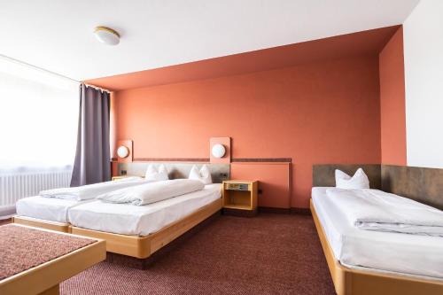 two beds in a hotel room with orange walls at Eibacher Hof in Nürnberg