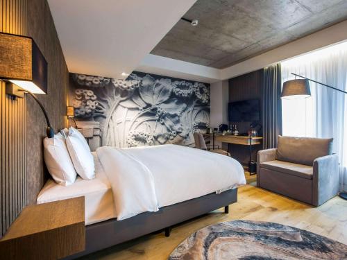 een slaapkamer met een groot bed en een stoel bij Mercure Riga Centre in Rīga