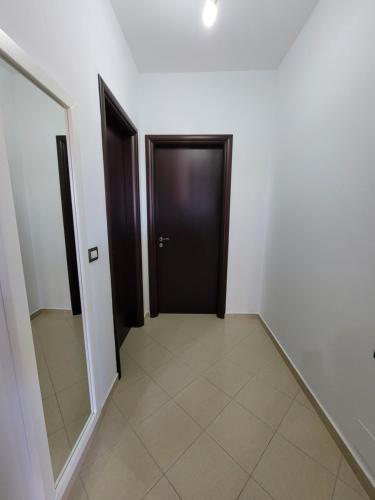 Un pasillo con una puerta negra y suelo de baldosas. en Vila Anja, en Ksamil
