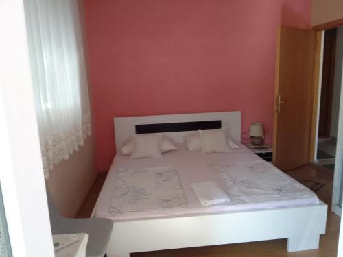a bedroom with a white bed in a red wall at Biba in Mostar