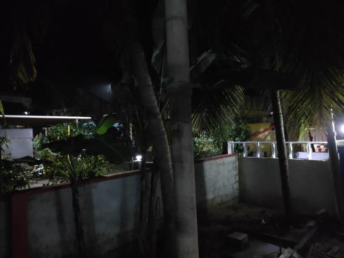a fence and palm trees at night at Gruham Malpe Beach Homestay Udupi in Malpe