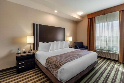 a hotel room with a large bed and a large window at Best Western Plus Drayton Valley All Suites in Drayton Valley