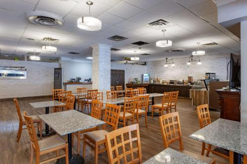 a restaurant with wooden tables and chairs and a kitchen at Quality Inn Toronto Airport in Mississauga
