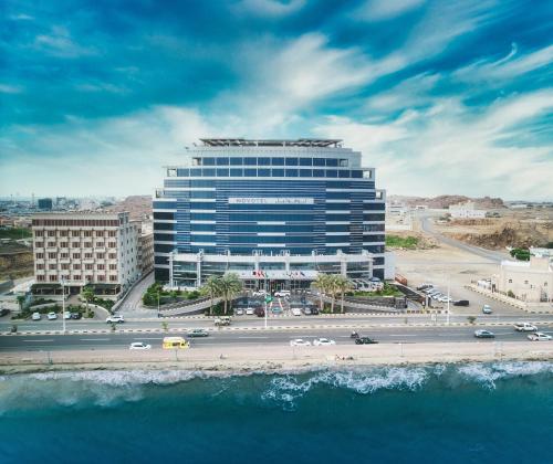 a large building next to a road and the ocean at Novotel Jazan in Jazan